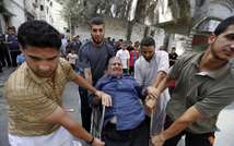 Des jeunes Palestiniens aident une personne âgée à évacuer son habitation après avoir reçu une alerte d'un prochain bombardement sur Gaza, le 12 juillet 2014 ( Mohamed Abed (AFP) )
