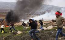 Palestinian protesters take cover from tear gas thrown by Israeli security forces during clashes following a demonstration against Israeli settlements in the West Bank village of Turmus Aya, north of Ramallah on December 19, 2014 (Abbas Momani (AFP))