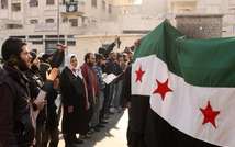 Rebel fighters and inhabitants of Aleppo demonstrate with a pre-Baath Syrian flag, now used by the Syrian opposition, on January 10, 2014 outside a compound of the Islamic State of Iraq and the Levant's (ISIL) ( Mohammed Wesam (Aleppo Media Centre/AFP) )