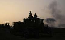Israeli soldiers sit atop D9 Armored Bulldozers position along the Israeli Gaza border on July 12, 2014, watching smoke rising following Israeli air strike into the Gaza Strip ( Menahem Kahana (AFP) )