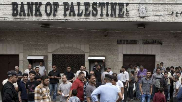 Hamas security forces in Gaza City stand guard as employees paid by the Palestinian Authority wait to receive their salaries outside a closed bank, on Thursday, June 5, 2014
