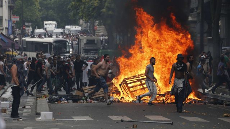 Protesters run by a fire barricade near the aerial metro station of Barbes-Rochechouart, in Paris, on July 19, 2014