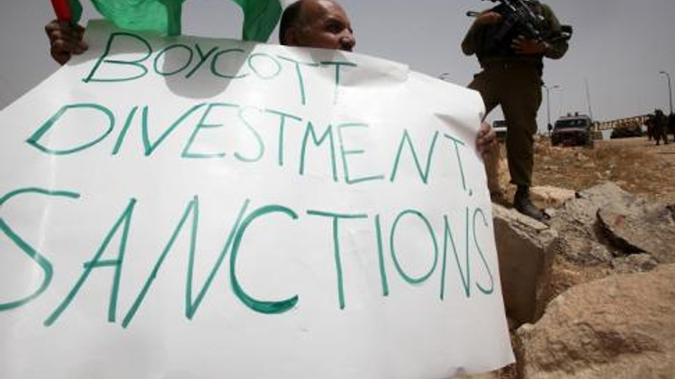 Un Palestinien tient un panneau portant l'inscription "Boycott, Divestment, Sanctions" (BDS) près de la colonie israélienne de Bat Ayin, à l'ouest d'Hébron (Cisjordanie), le 8 juin 2013
