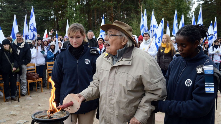 Two Israeli soldiers help Samuel Willenberg, the only living survivor of an August 1943 prisoner rebellion at Treblinka, to light a candle in a memorial ceremony at the camp on October 2, 2013.