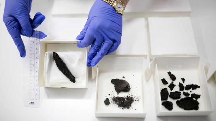 An Israel Antiquities Authority worker displays a scroll (L), found in 1970, along with other findings, that are yet to be analysed, at the Israel Museum in Jerusalem July 20, 2015.