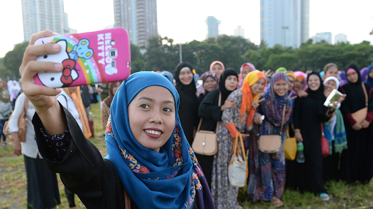 Muslim women pose for a selfie after attending prayers during Eid al-Adha celebrations at a park in Manila, the Philippines