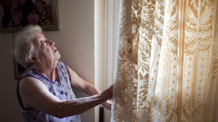 Holocaust survivor looks out window of her home in Ashkelon after rocket fell nearby