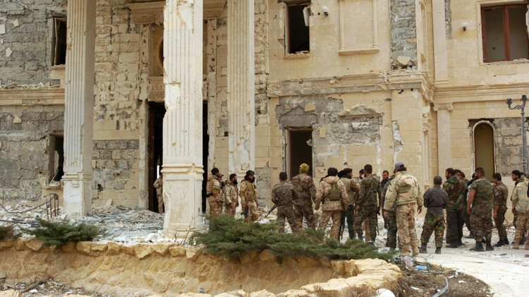 Syrian troops stand next to a mansion in the ancient city of Palmyra on March 24, 2016