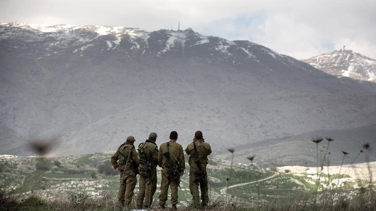 Israeli soldiers deployed on the border with Syria observe Syrian territory from Israeli side of the border near the Druze village of Majdal Shams, on March 19, 2014