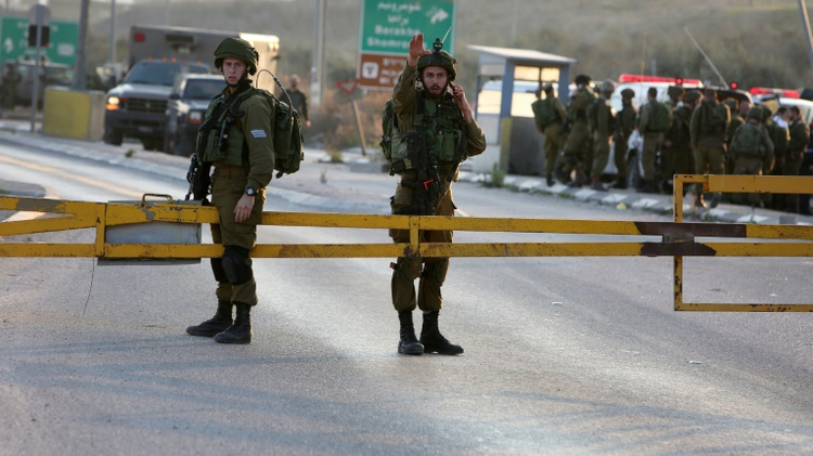 Israeli security forces stand guard at the site of a car ramming attack at the Huwara checkpoint near the West Bank city of Nablus, on December 26, 2015