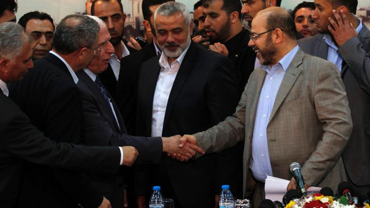 Palestinian Fatah envoy Azzam al-Ahmed (left) shakes hands with Hamas deputy leader Musa Abu Marzuk (right) in the presence of Hamas prime minister Ismail Haniya (centre) after signing a reconciliation agreement in Gaza City, on April 23, 2014