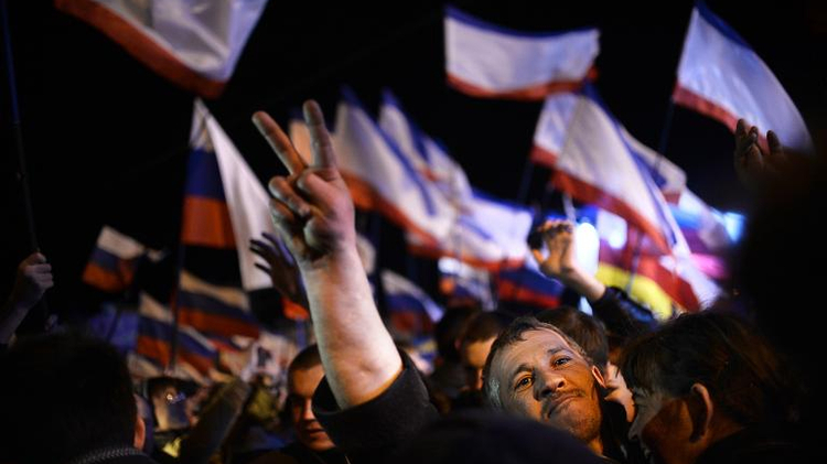 A picture taken on March 16, 2014 shows a Crimean man making the victory sign as he celebrates in Simferopol's Lenin Square after exit polls showed that about 93 percent of voters in Ukraine's Crimea region supported union with Russia