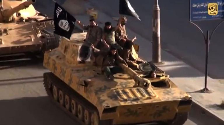 A screen grab taken from a video released on July 1, 2014, allegedly shows members of the IS (Islamic State) parading on top of a tank on a street in the northern rebel-held Syrian city of Raqa