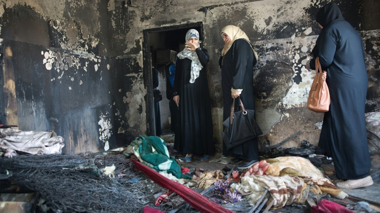 Palestinian women look at the damage to a home in the West Bank village of Duma on August 4, 2015, after it was set on fire by suspected Jewish extremists killing 18-month-old Ali Saad Dawabsha