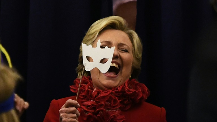 La candidate démocrate à la Maison Blanche Hillary Clinton sourit en portant un masque à bord de son avion pour la campagne électorale le 31 octobre 2016 à Erlanger Kentucky