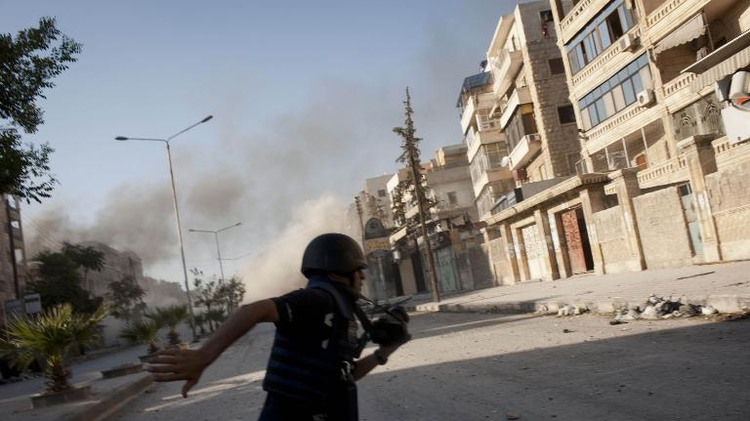 A reporter, identified as Medyan Dairieh, runs after being injured in the leg, across a sniper corridor during heavy fighting in the Saif al-Dawla district of Aleppo, Syria, on August 24, 2012