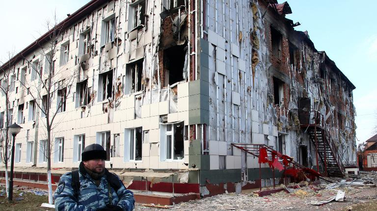 A serviceman guards a school building damaged during fighting between militants and police, in Grozny, Chechnya, on December 5, 2014