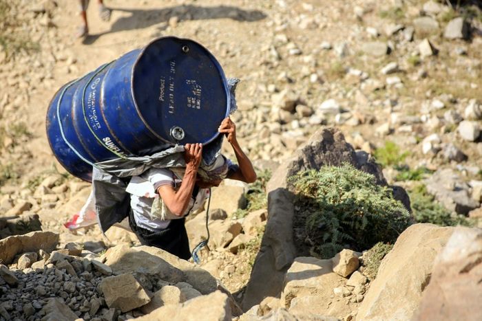 A Yemeni man carries a barrel of supplies as he walks through the mountains along the only path accessible between the southern cities of Aden and Taez on December 26, 2015. AFP PHOTO / AHMAD AL-BASHA