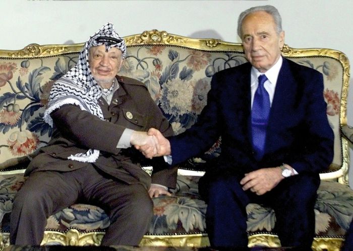 L'ancien leader de l'autorité palestinienne, Yasser Arafat, serre la main de Shimon Peres, au Caire le 15 juillet 2001 Marwan NAAMANI (AFP/Archives)