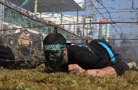 Palestinian youngsters crawl under a barbed wire obstacle during a graduation ceremony for a training camp run by the Hamas movement, in Khan Yunis, in the southern Gaza Strip - Said Khatib (AFP) Said Khatib (AFP)