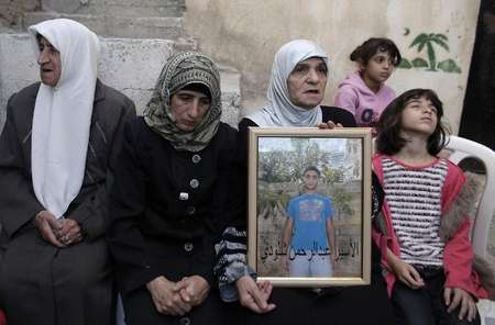 The mother (2L) and other family members of Palestinian Abdelrahman Shaludi, who killed a baby in a car attack, hold his portrait at their family home in east Jerusalem on October 23, 2014 - Ahmad Gharabli (AFP) Ahmad Gharabli (AFP)
