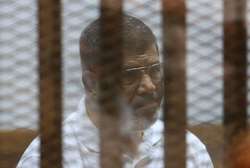 Le président islamiste Mohamed Morsi destitué par l'armée, derrière les grillages du banc des accusés lors de son procès au Caire le 18 août 2014 - Str (AFP/Archives) Str (AFP/Archives)