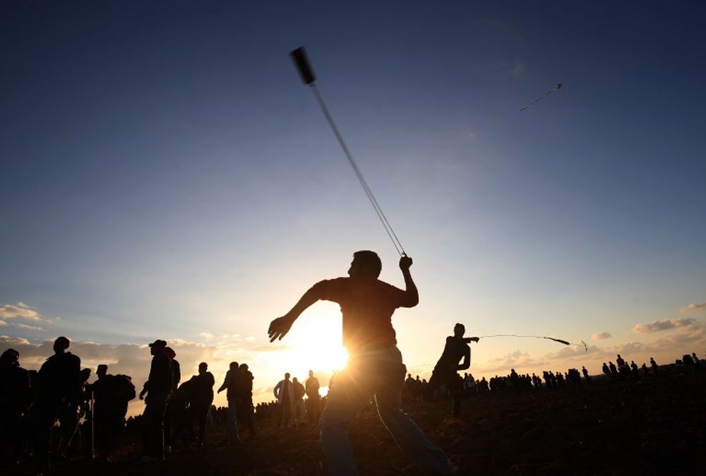 Palestinian protesters use slingshots to hurl stones during a demonstration near the border between Israel and Khan Yunis in the southern Gaza Strip, on December 21, 2018