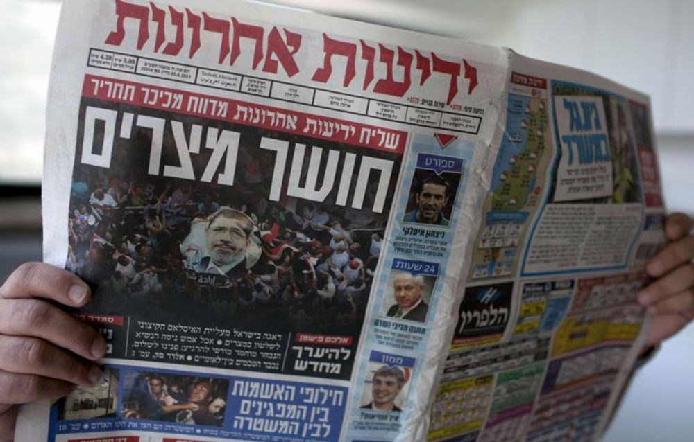 A man reads the Israeli daily newspaper, Yediot Aharonot, displaying the front cover's headline reading in Hebrew: "Darkness in Egypt," in Jerusalem on 25 June 2012.