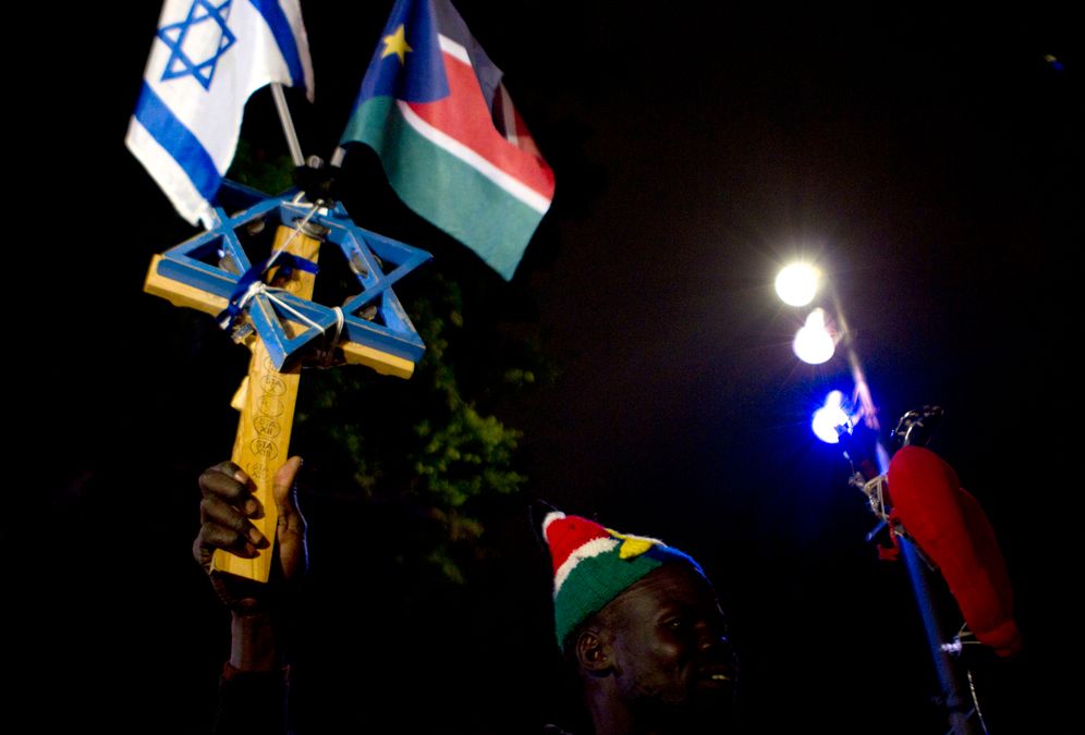 A South Sudanese man holds an Israeli and a South Sudan flags as he protest against Israel's government decision to deport 700 South Sudanese asylum seekers back to South Sudan by the end of March, in Tel Aviv, Israel, Saturday, March 17, 2012.