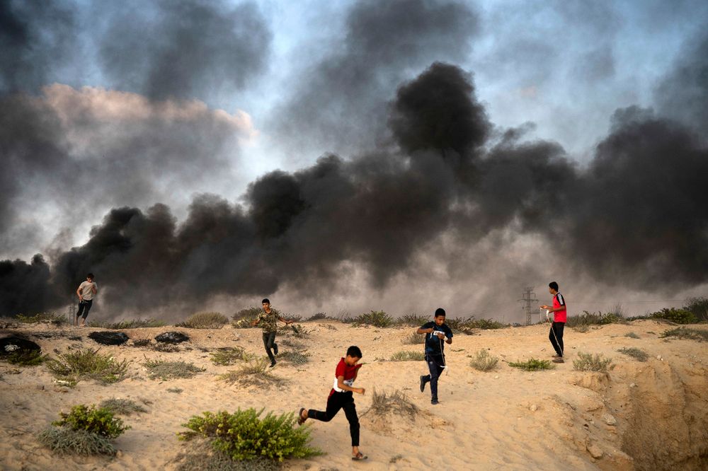 Young Palestinian protesters run from tear gas fired by Israeli soldiers during a protest on the beach near the border with Israel in Beit Lahiya, northern Gaza Strip, Monday, Sept. 10, 2018.