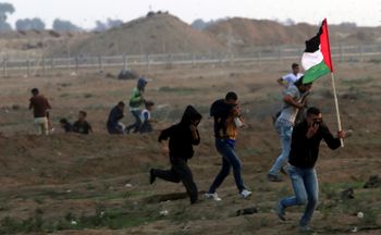 Protester run to cover from teargas fired by Israeli troops near fence of Gaza Strip border with Israel during a protest east of Gaza City, Friday, Nov. 9, 2018.