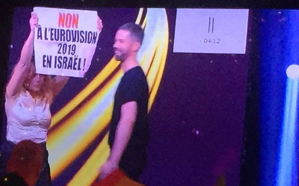A protester holds a sign reading "No to Eurovision 2019 in Israel" in Paris