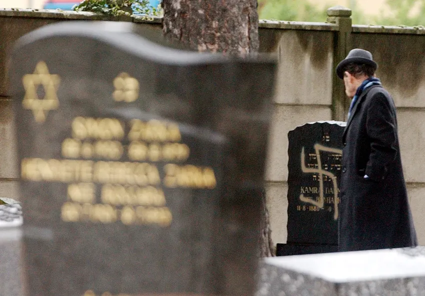 FILE: An unidentified French member of the Jewish community looks at a grave marked with a swastika Sunday, April 14, 2002 in the Jewish cemetery of Strasbourg-Cronenbourg, in Strasbourg, eastern France. About 20 graves were marked with swastikas on Frida