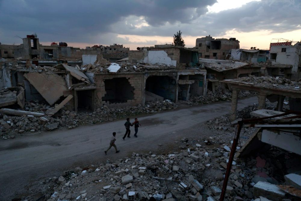 Syrian children walk past heavily damaged buildings in the rebel-held town of Douma, on the eastern edges of Damascus on February 27, 2016