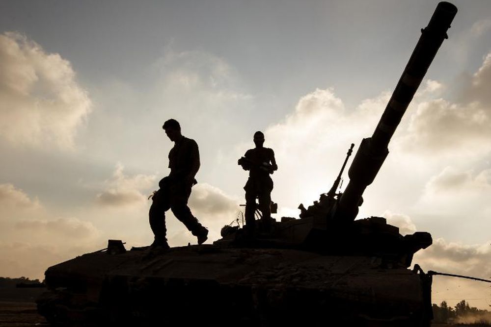 Israeli soldiers stand on a Merkava tank stationed at an army deployment along the border with the Gaza Strip.