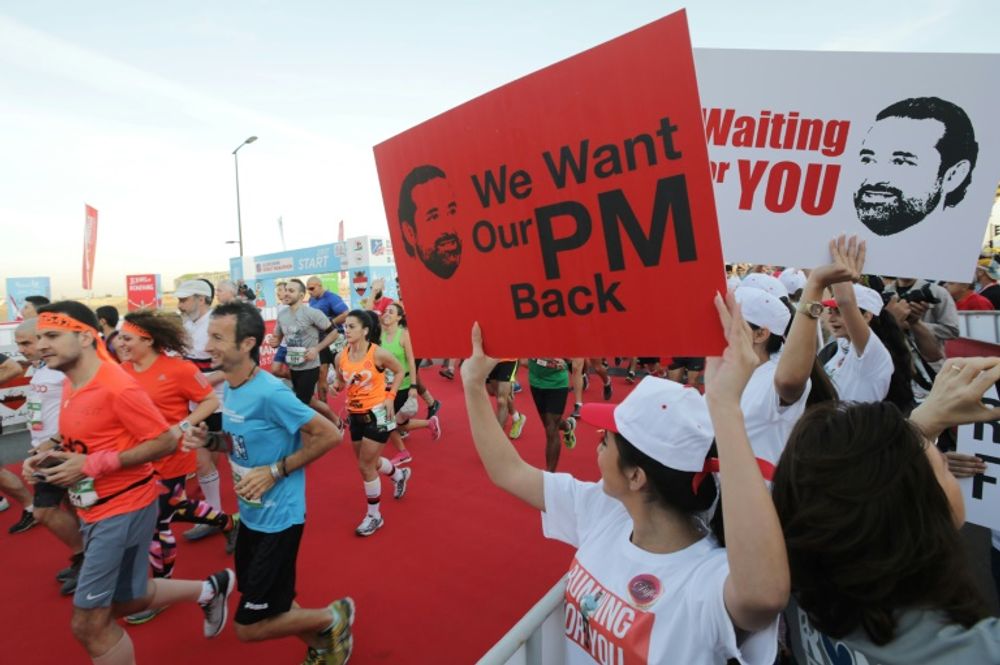 Des Libanaises brandissent des pancartes demandant le retour du Premier ministre démissionnaire Saad Hariri au Liban lors du marathon de Beyrouth, le 12 novembre 2017