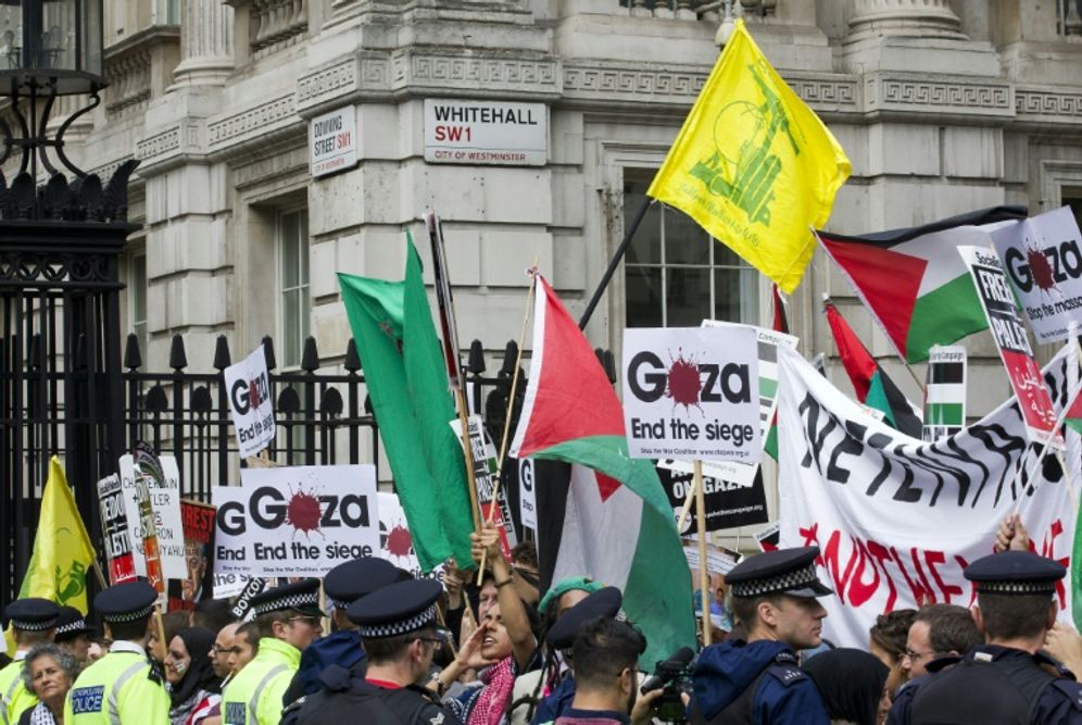 Pro-Palestinian demonstrators carry Palestinian flags and the yellow flag of Lebanese Shiite militant group Hezbollah as they rally outside the gates of Downing Street in London on September 9, 2015