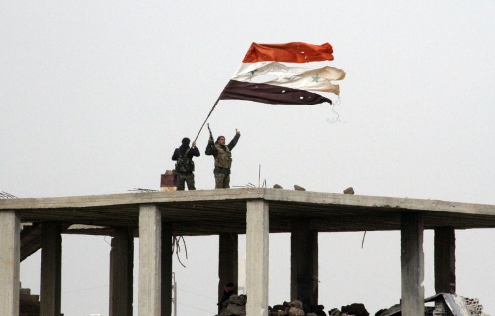 Syrian government forces wave the national flag in Deir al-Adas in the Daraa province on February 11, 2015 after President Bashar al-Assad's army, backed by Hezbollah and Iranian officers, pushed rebels out of the area