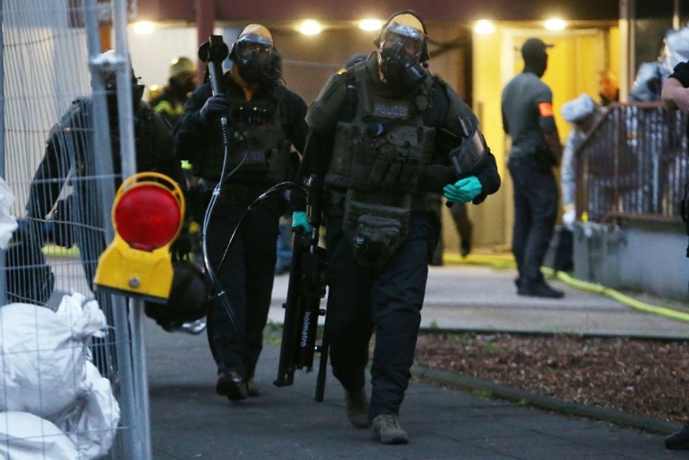 German special forces wearing protective suits walk out of a Cologne building where police arrested a Tunisian man after discovering "toxic substances" in his flat
