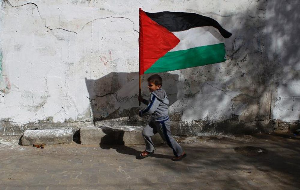 A child runs with the Palestinian flag as friends and relatives prepare for the release of prisoner Ramy Barbakh, 37, outside his home in Khan Yunis, in the southern Gaza Strip, on December 29, 2013