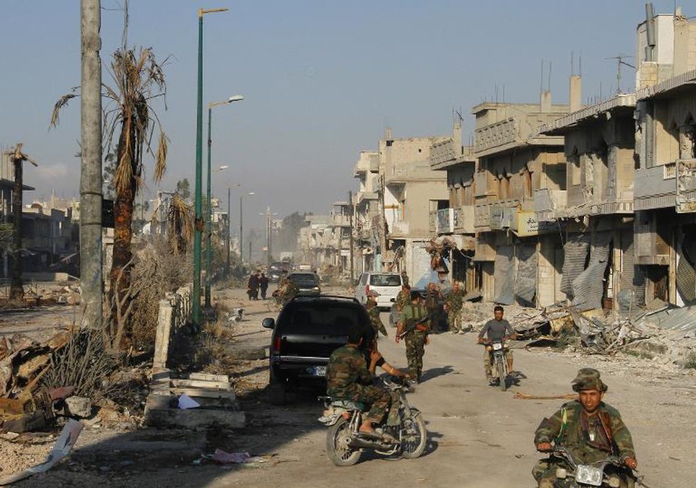 File photo of Syrian army troops patrolling a ravaged street in Qusayr in Syria's central Homs province on June 5, 2013