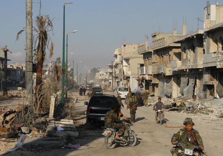 Syrian army troops patrol a ravaged street in Qusayr in Syria's central Homs province on June 5, 2013