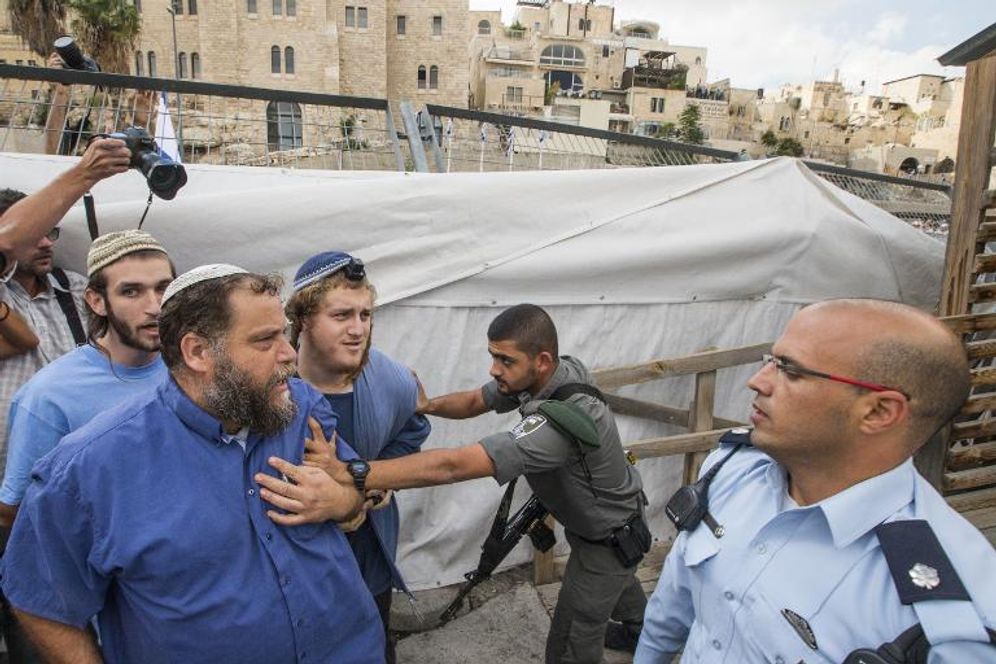 Un garde-frontière repousse des membres de Lehava, dont le chef Bentzi Gopstein (2e à g), qui tentent d'accéder à l'esplanade des Mosquées, temporairement fermée au public, le 30 octobre 2014