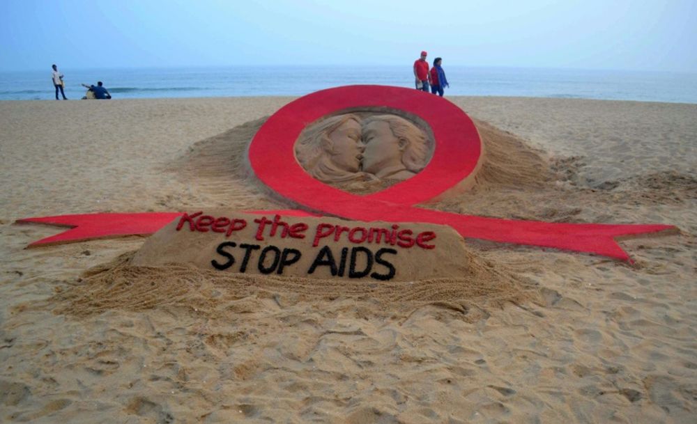 An Indian couple walks past a sand sculpture on the eve of World AIDS Day in Puri, India on November 30, 2015