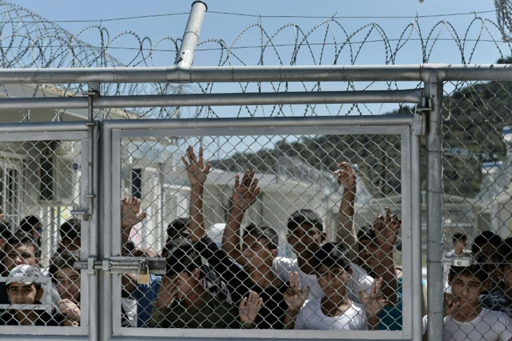 Young migrants and refugees at a fence in the Moria detention center on the Greek island of Lesbos, on April 16, 2016