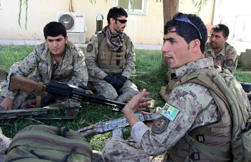 Afghan security personnel talk as they perpare to launch a counter-offensive to retake the city from Taliban insurgents at the airport in Kunduz on September 30, 2015