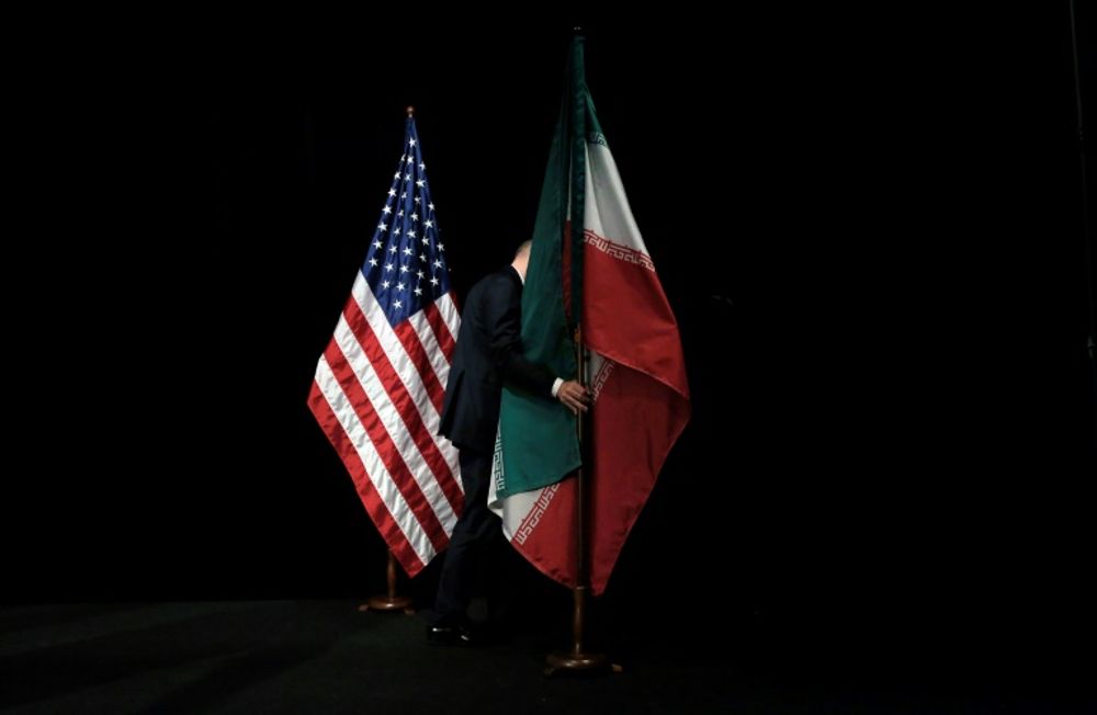 A staffer removes the Iranian flag from the stage after a group picture with foreign ministers and representatives of the United States, Iran, other nations and the European Union on July 14, 2015, when the Iran nuclear deal was signed