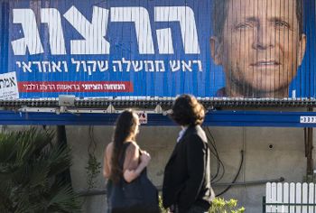 People look at a giant campaign billboard showing Israeli MP Labour Party leader and co-leader of the Zionist Union party Isaac Herzog on March 14, 2015, in the coastal Israeli city of Tel Aviv