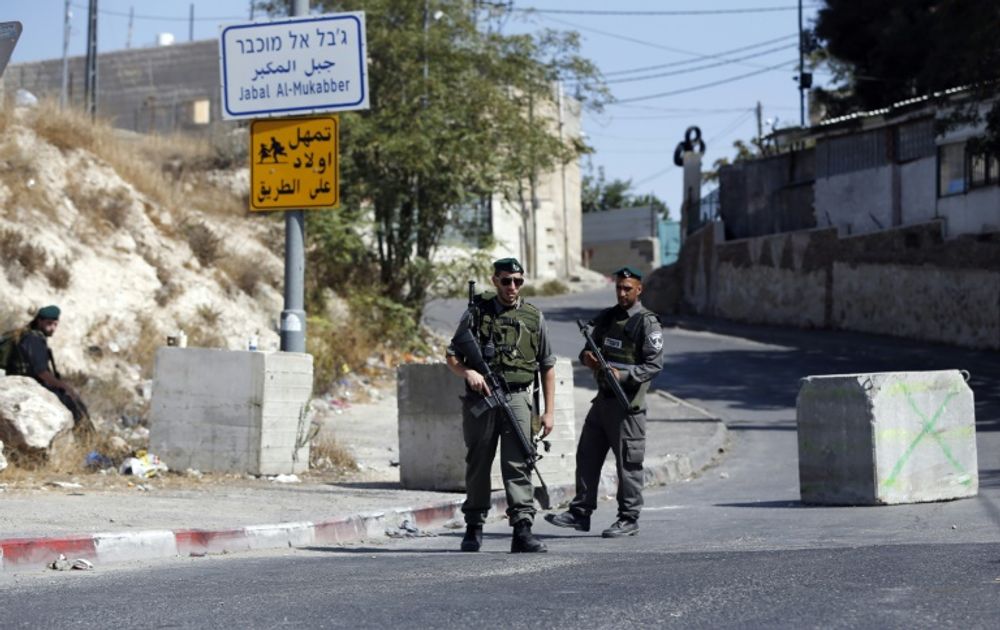 Israeli border guards stand at a roadblock set up on a road close to the Palestinian neighborhood of Jabal Mukaber in east Jerusalem.