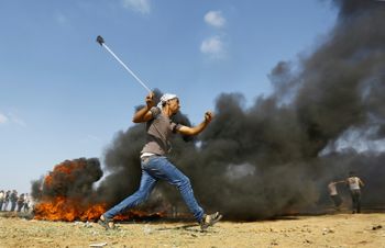 A Palestinian man hurls a stone during clashes with Israeli forces on May 15, 2018 near the border fence with Israel east of Jabalia in the central Gaza Strip